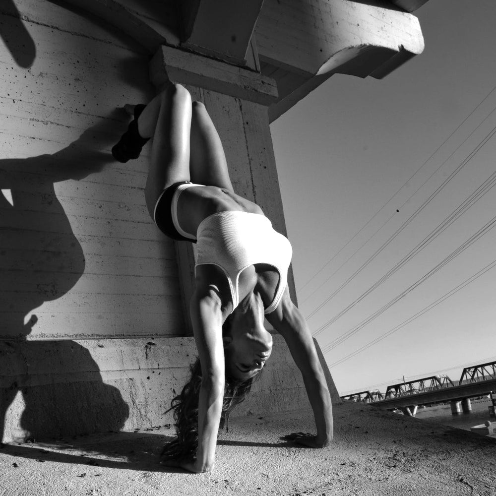 Person doing a handstand under a bridge with power lines in the background