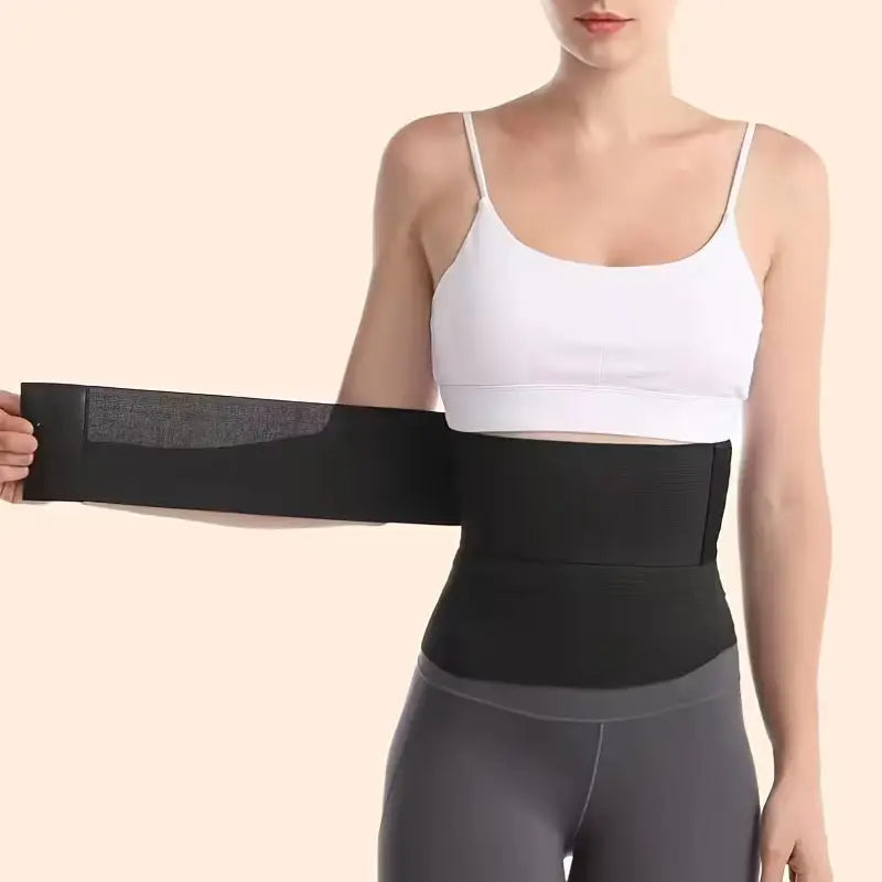 A person wearing a black waist trainer with a plain background demonstrating the stretch of trainer